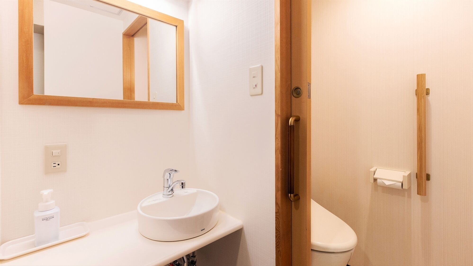 Un baño con lavamanos, espejo y retrete blancos.