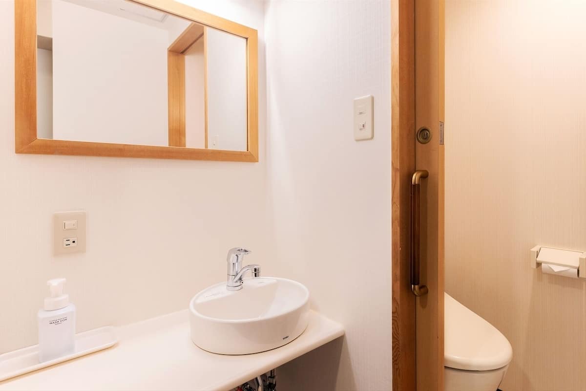 Un bagno con lavandino, specchio e WC bianchi.
