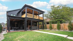Une maison à deux étages avec un patio couvert et une cour arrière clôturée.