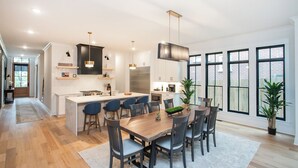 Une cuisine moderne dotée d’un îlot central, de tabourets de bar et de luminaires suspendus.