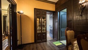 A hallway with wooden flooring, a glass-fronted cabinet, and a door leading to another room.