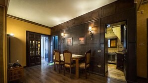 A dining area with a wooden table and chairs, a cabinet with glass doors, and wall-mounted lights.