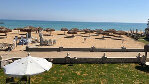 Una playa con sombrillas de paja, sillas de descanso y una vista despejada del mar.