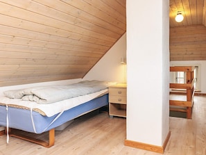Une petite chambre à coucher accueillante, avec un plafond en pente, un lit simple, une table de chevet et une commode.