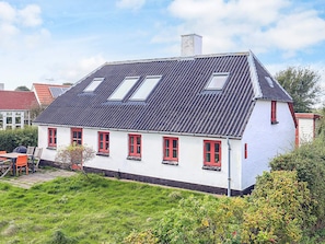 A two-story house with a sloped roof, multiple windows, and a garden in the foreground. - 5 Person Holiday Home in Veslos (Vesløs)