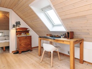 A cozy attic bedroom with a sloped ceiling, a skylight, a wooden desk, a white chair, and a vintage dresser. - 5 Person Holiday Home in Veslos (Vesløs)