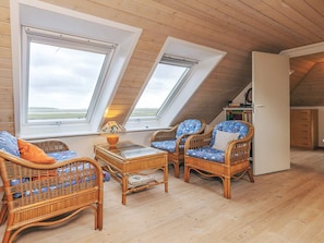 Une chambre à l’étage, aménagée dans un style chaleureux, avec un plancher en bois, un plafond en pente et deux fenêtres de toit.