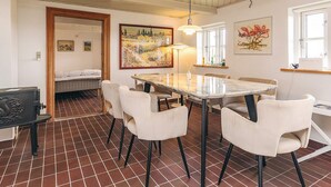 A dining area with a marble table and white chairs, a painting on the wall, and a window with a view. - 5 Person Holiday Home in Veslos (Vesløs)
