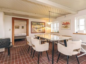 Un comedor con una mesa de mármol y sillas blancas, un cuadro en la pared y una ventana con vistas.