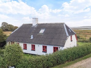 Une maison blanche avec des fenêtres rouges et un toit en pente.