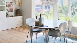 Un espace repas moderne avec une table ronde, des chaises blanches et un tapis bleu.