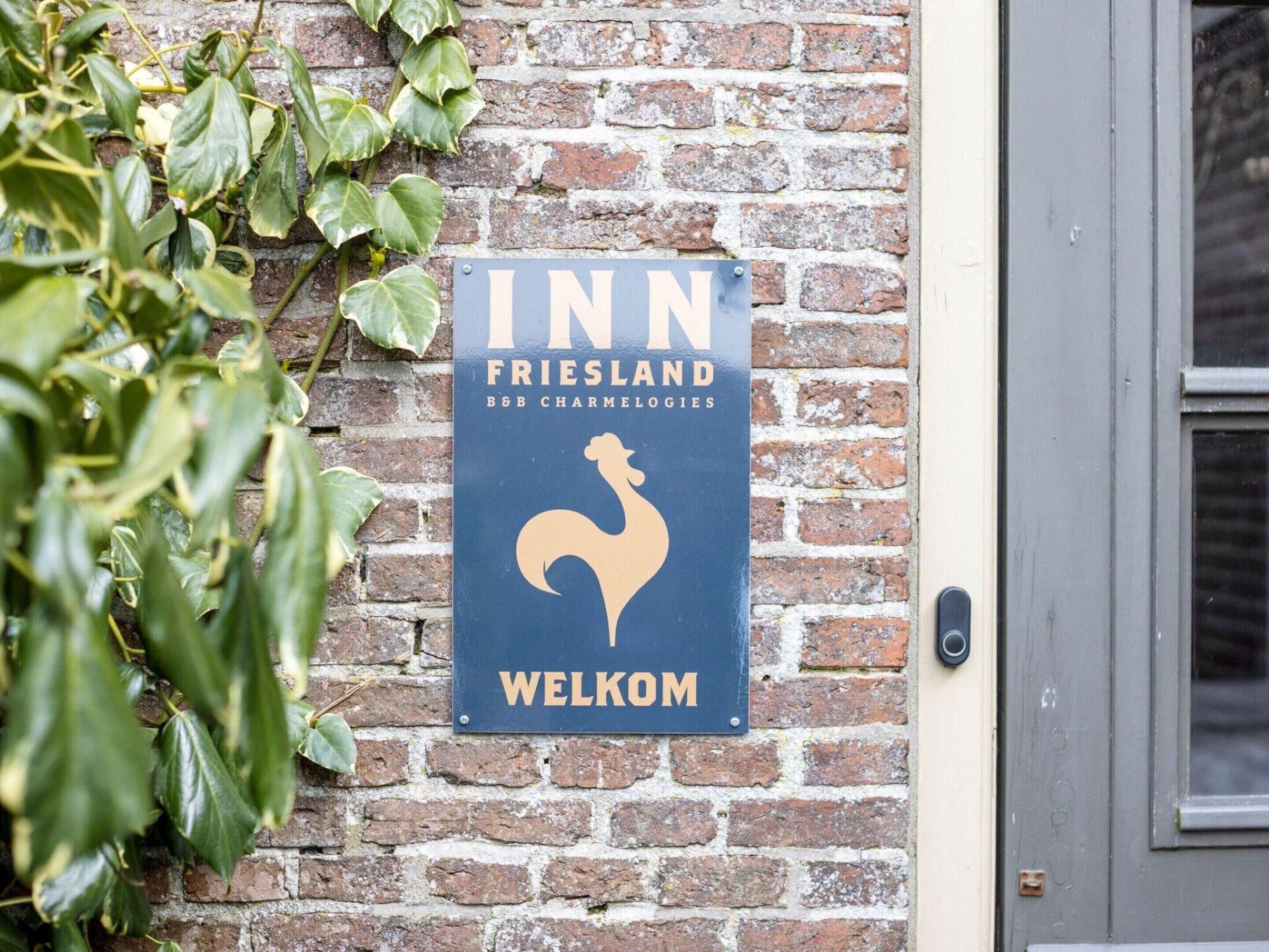 A sign for 'INN FRIESLAND' with a rooster symbol and the word 'WELKOM' on a brick wall.