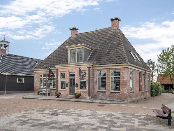 A brick building with a gabled roof, large windows, and a flag. - Historic 17-guest Inn Near Heritage (Ternaard)