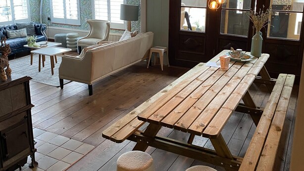 Un vaste espace de vie comprenant une table à manger en bois, deux tabourets et un canapé.