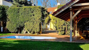 Ein Garten mit Schwimmbad, einer Holzpergola und einem gepflegten Rasen.