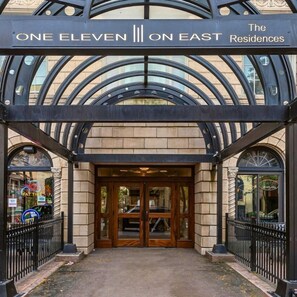 The entrance to One Eleven on East Residences with a glass canopy and a sign above the doors. - East 116 I Corporate 1Bd Suite in Rochester I Gym (Rochester)