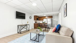 A modern living room with a sofa, coffee table, and a TV mounted on the wall. - East 120 I Modern Refinished Apt Downtown I Gym (Rochester)