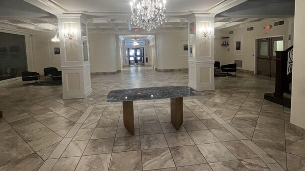 A spacious lobby with a marble floor, a central bench, and a chandelier. - East 120 I Modern Refinished Apt Downtown I Gym (Rochester)