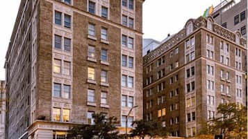 A multi-story hotel with a classic architectural style, featuring a prominent corner entrance and a visible stop sign at the intersection.