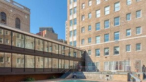 A courtyard with a pool, a modern building with large windows, and a historic building in the background. - East 120 I Modern Refinished Apt Downtown I Gym (Rochester)