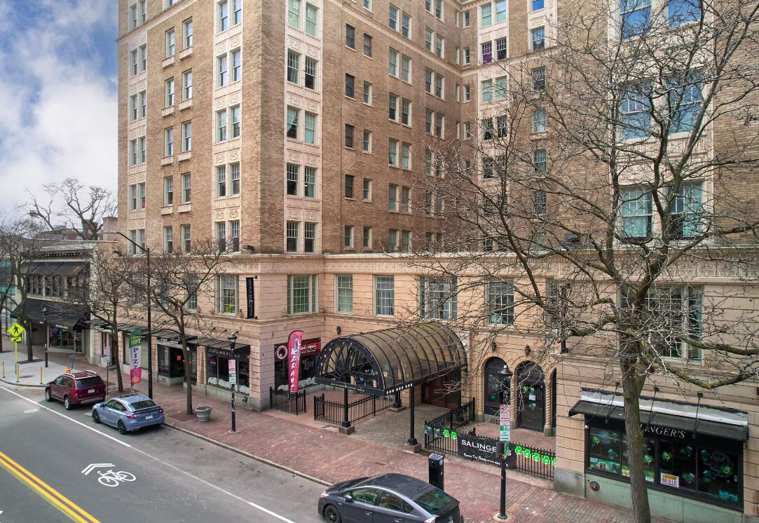A multi-story hotel with a brick facade, a covered entrance, and a street view with cars and a bike lane.