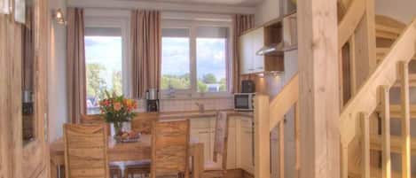 Un interior de madera con comedor, cocina y escalera.