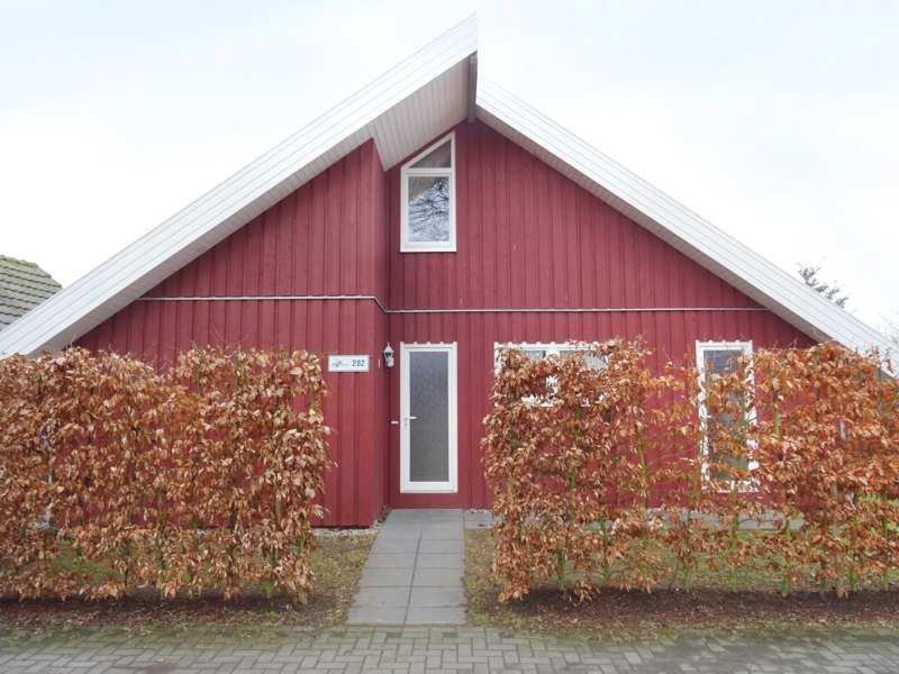 A red building with a gabled roof, a small door, and a window.