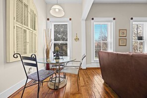 A dining area with a glass table, metal chairs, a brown sofa, and a chandelier. - Newly renovated near Bourbon Trail & attractions! (Louisville)