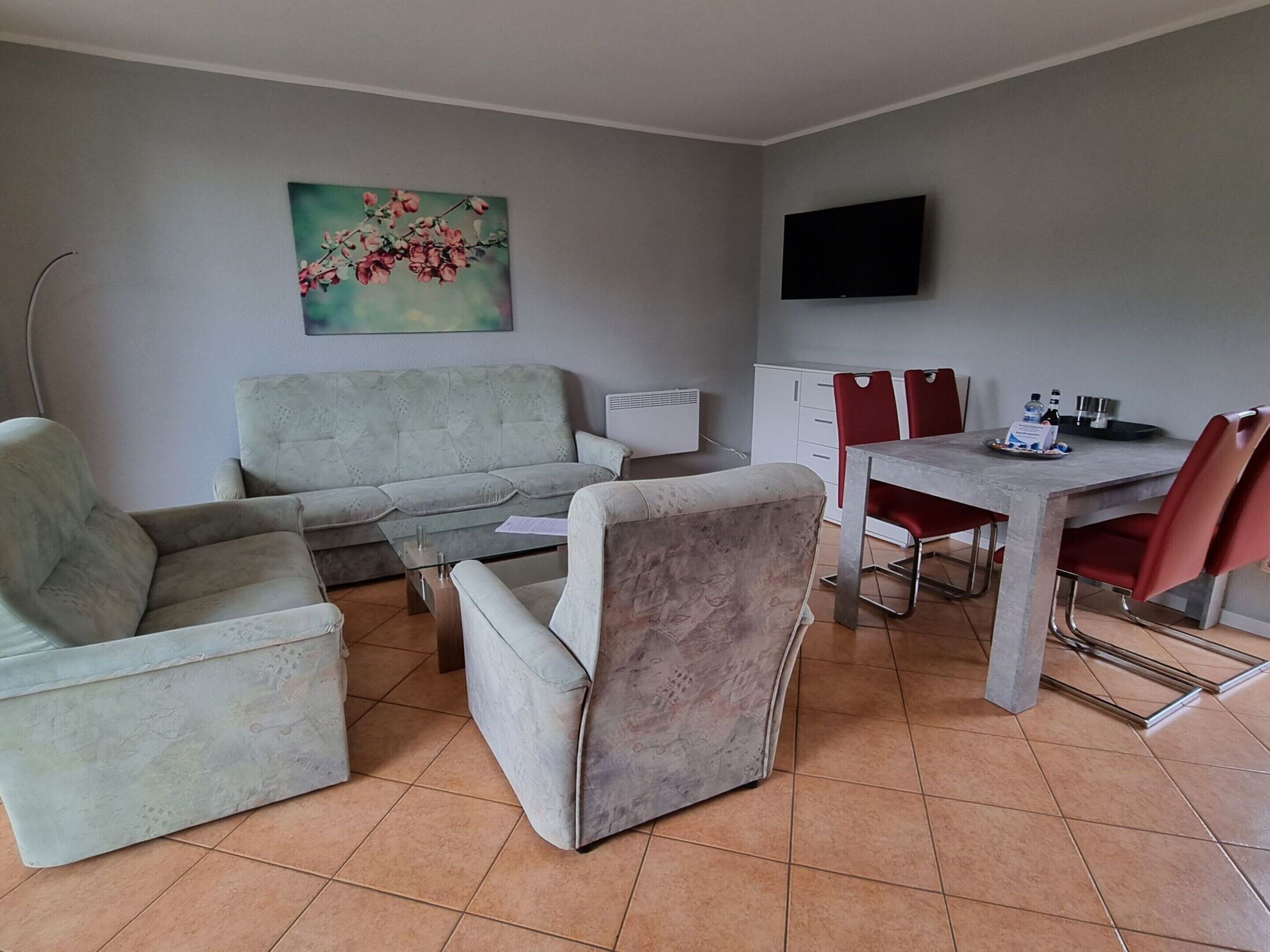 A living room with a sofa, armchairs, a coffee table, and a dining area with a table and chairs.