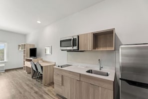 Eine moderne Küche mit Mikrowelle, Kühlschrank und einer Holzausziehtheke.