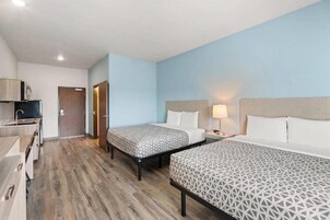 Habitación de hotel con dos camas, un escritorio y una kitchenette.