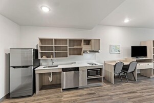 Una cocina moderna con electrodomésticos integrados, un comedor con mesa y sillas, y un televisor de pantalla plana.