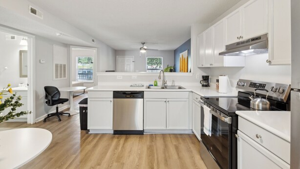 A modern kitchen with white cabinetry, stainless steel appliances, and a central island. - CB 3504-103 Fayetteville Oasis I Modern, Comfy (Fayetteville)