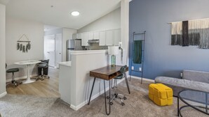A modern kitchen with white cabinets, a central island, and a dining area with a table and chairs.