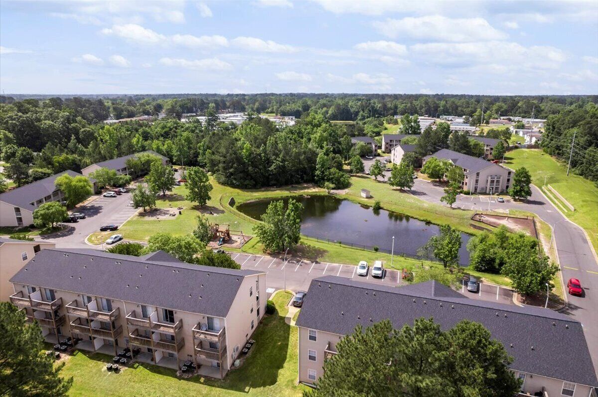 A residential area with apartment buildings, a central pond, and surrounding greenery.