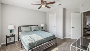 A bedroom with a bed, two bedside tables, a ceiling fan, and a door. - CB 3508-304  Fayetteville Oasis I Modern, Comfy (Fayetteville)