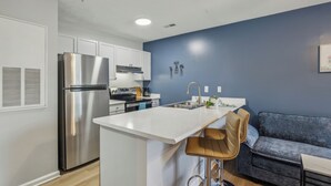 Uma cozinha moderna com geladeira de aço inoxidável, armários brancos e uma parede azul decorativa.