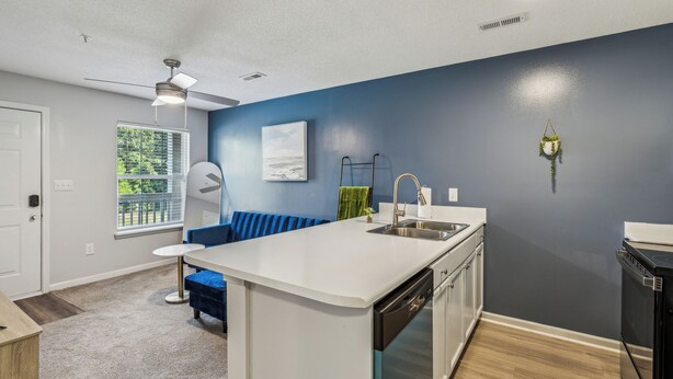 Une cuisine moderne avec un îlot central blanc, un lave-vaisselle encastré et un mur d’accent bleu.
