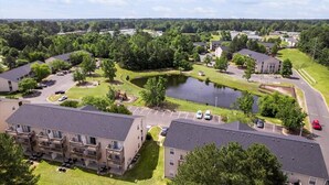 Un quartier résidentiel composé d’immeubles d’appartements, d’un étang central et d’espaces verts environnants.