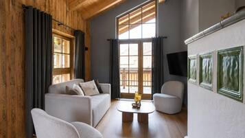 Ein modernes Wohnzimmer mit Holzboden, einer Sofagarnitur, einem Couchtisch und einem an der Wand befestigten Fernseher.