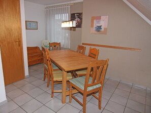 Un comedor con una mesa y sillas de madera, un sofá y una ventana con cortinas.