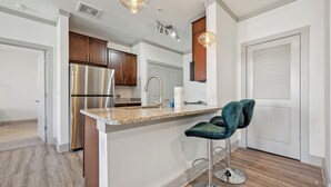 A modern kitchen with stainless steel appliances, a granite countertop, and a bar stool.