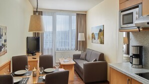 A modern hotel room with a dining area, a sofa, a television, and a kitchenette. - Appartements im Freizeitpark Weissenhauser Strand (Wangels)