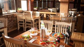 A restaurant with wooden tables and chairs, various dishes, wine glasses, and bottles.