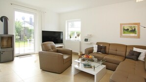Ein Wohnzimmer mit einer Couch, einem Sessel und einem Glastisch.