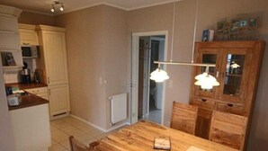 Eine Küche mit Holztisch und -stühlen, einem weißen Schrank und einer Tür zu einem anderen Raum.