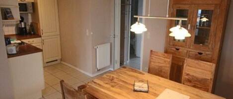A kitchen with a wooden table and chairs, a white cabinet, and a doorway leading to another room.