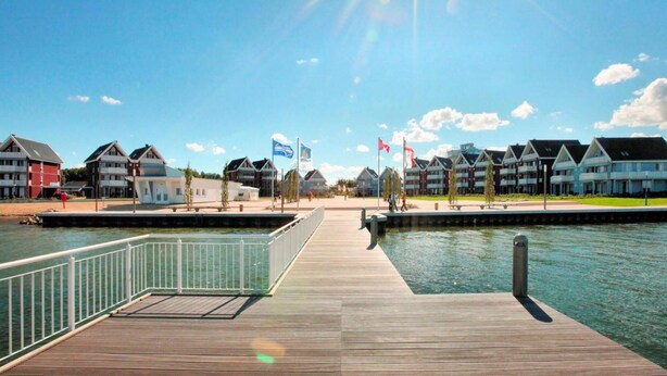 Ein Hotel am Wasserufer mit einer Holzsteganlage, mehreren Gebäuden und Flaggen.