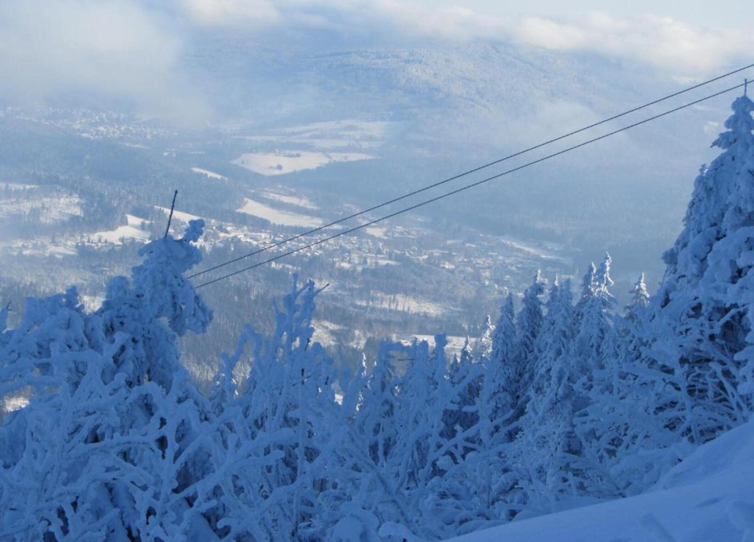 A snowy mountain landscape with a clear view of a town below.