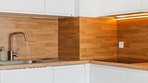 Eine moderne Küche mit weißen Schränken, einer Edelstahlspüle und einer Holzrückwand.